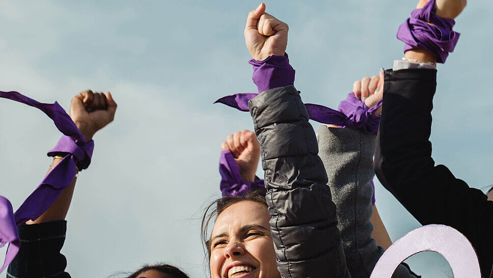 Frauen demonstrieren am Weltfrauentag mit einer lilafarbenen Armbinde