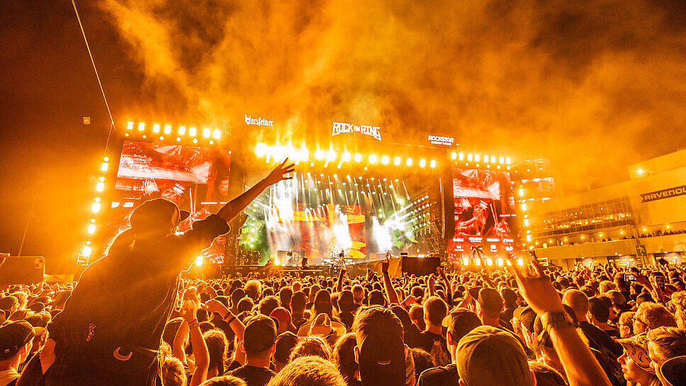 Eine große Menschenmenge vor der Bühne von Rock am Ring mit Lichteffekten und Nebel bei Nacht 