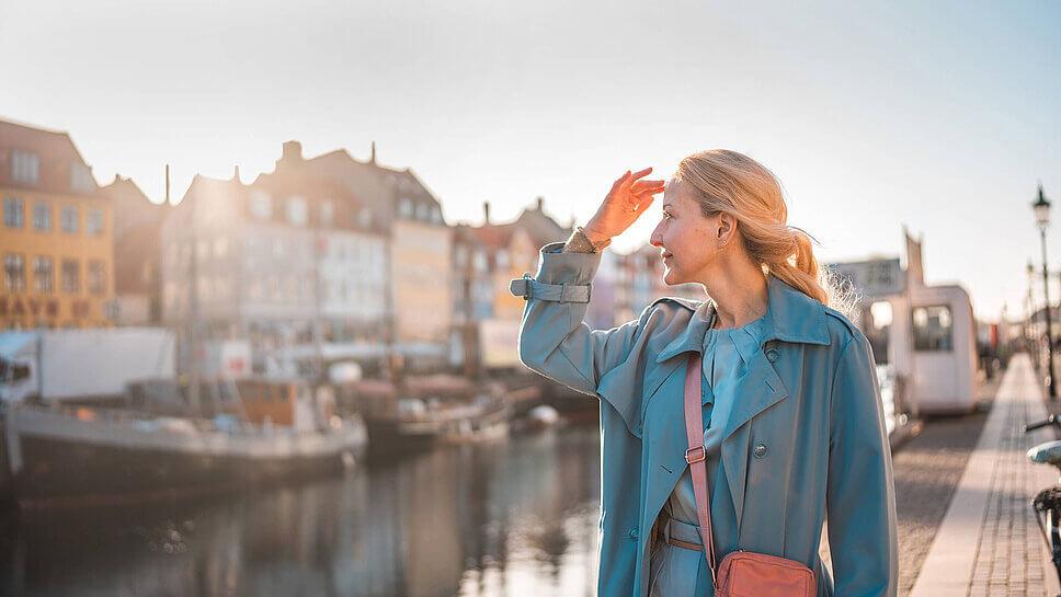 Frau in Mantel und mit Umhängetasche im Kopenhagener Viertel Nyhavn